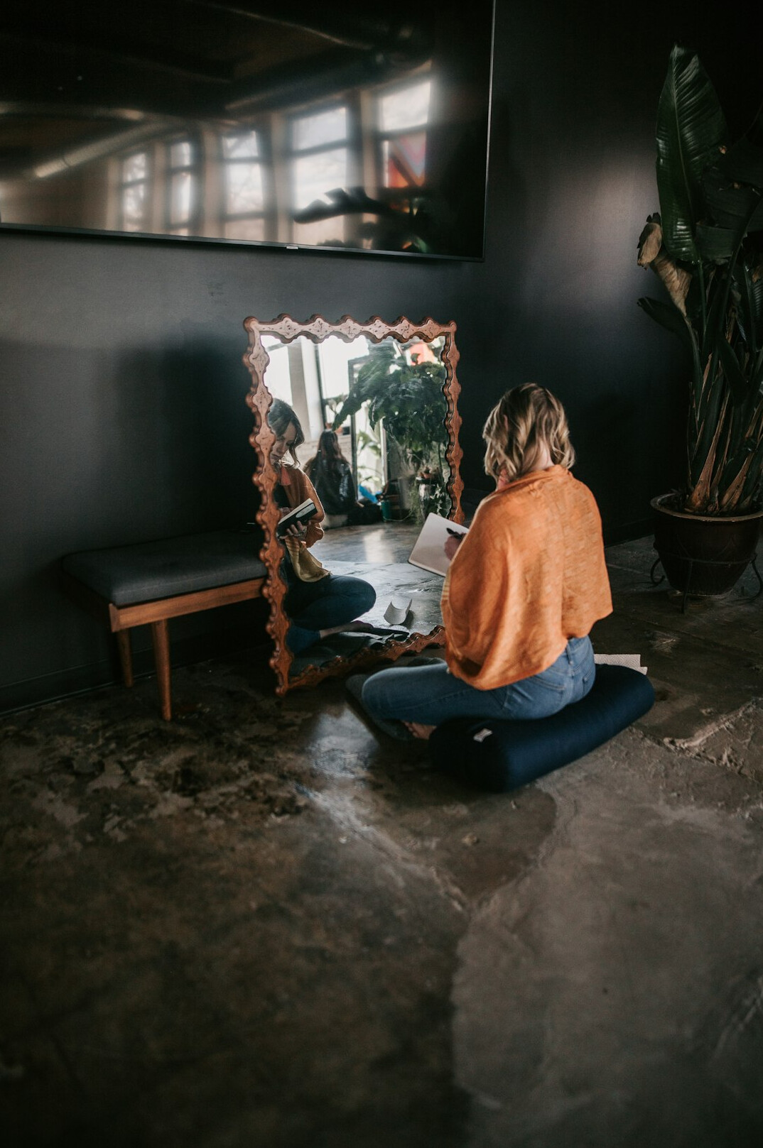 Brazilian woman writing reflections in a notebook near a window